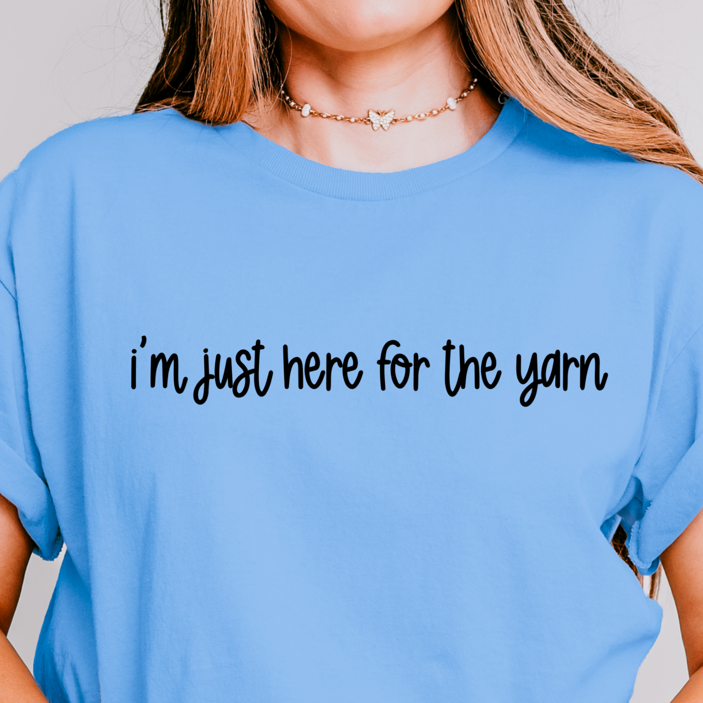 A person wearing a blue t-shirt with the text 'i'm just here for the yarn' printed on the front.