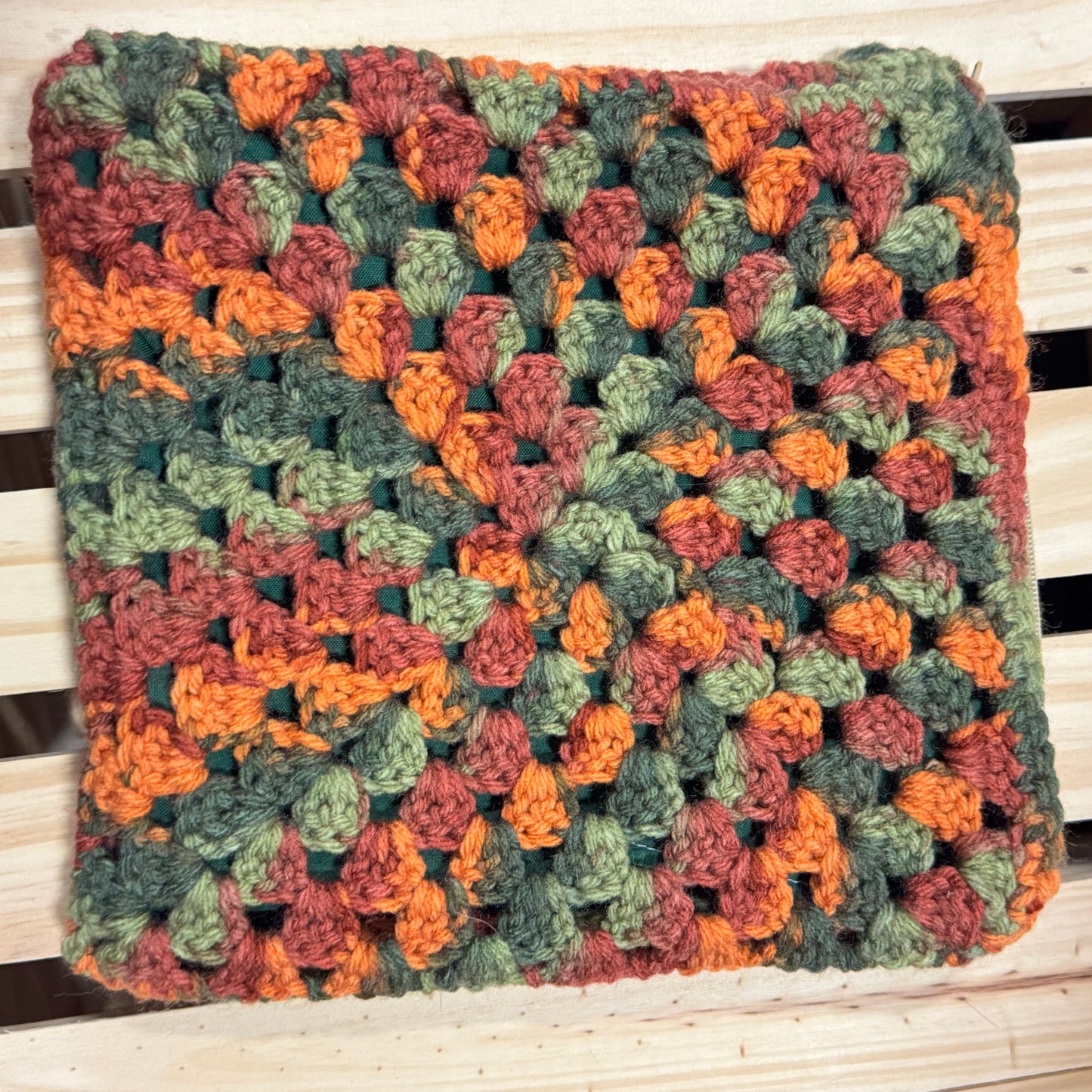 Multicolored crocheted pouch on a wooden surface