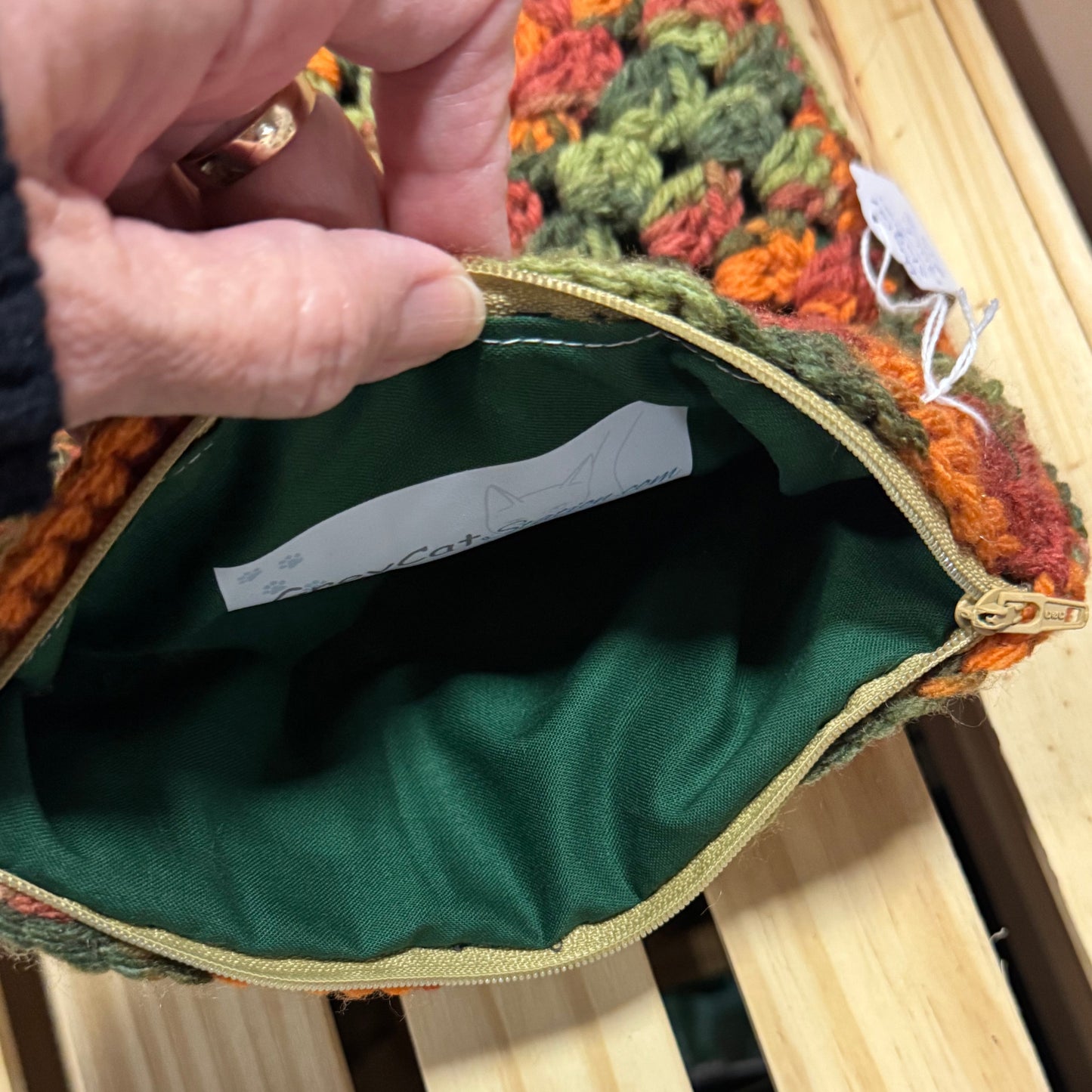 Close-up of a green fabric pouch with a textured surface on a wooden bench.