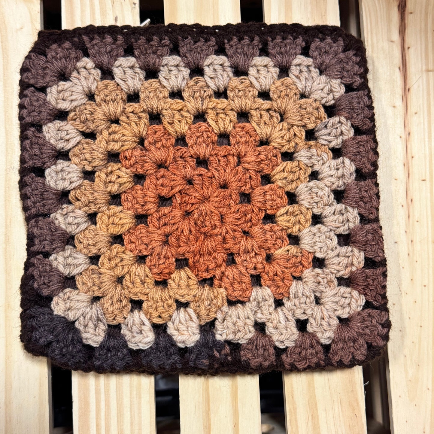 Crocheted pouch with a square pattern on a wooden surface