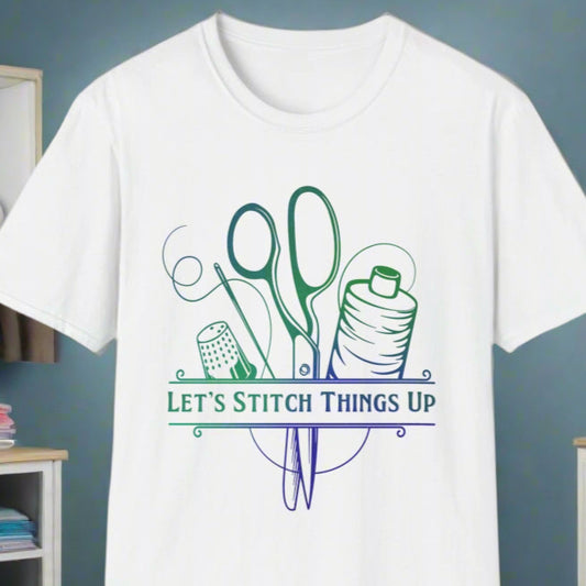 White t-shirt with a graphic that includes a pair of scissors, a spool of thread, and the text 'LET'S STITCH THINGS UP', displayed in a room with sewing-related items in the background.