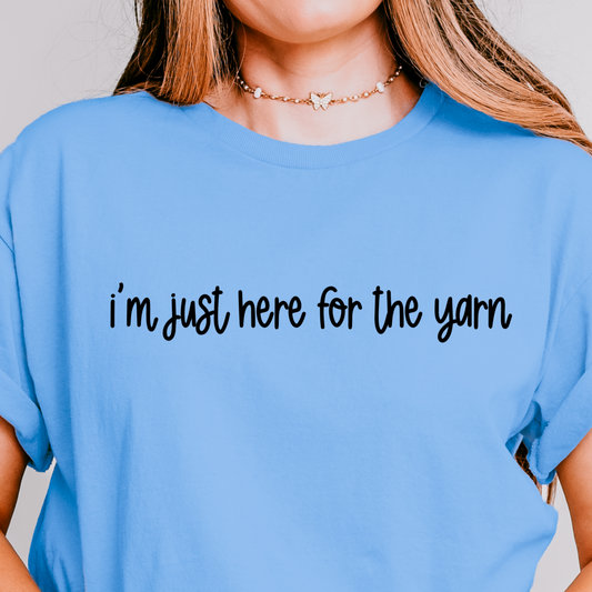 A person wearing a blue t-shirt with the text 'i'm just here for the yarn' printed on the front.