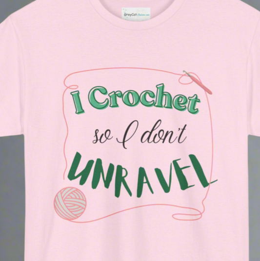 A pink T-shirt with the text 'I Crochet so I don't UNRAVEL' printed on the front, featuring a graphic of yarn and a crochet hook.