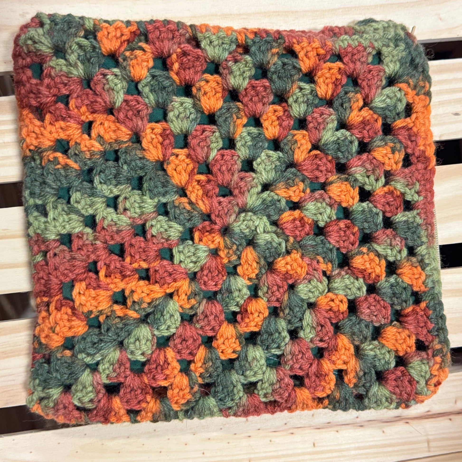 Multicolored crocheted pouch on a wooden surface