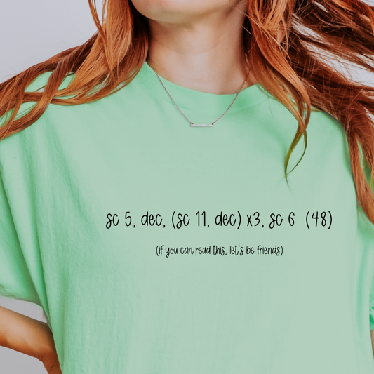 Person wearing a green t-shirt with text on it against a plain background